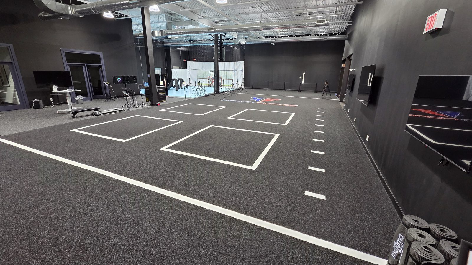 The ReactForge off-ice training floor: a turf surface marked with zones and read-and-react boxes, with screens and cameras set up around it.